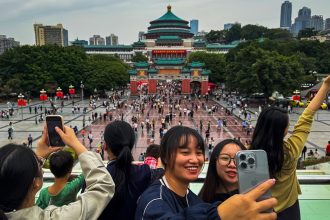 A group of young women take selfies in front of Chongqing's People’s Great Hall during the National Day Golden Week holiday on October 5, 2024, in Chongqing, China.