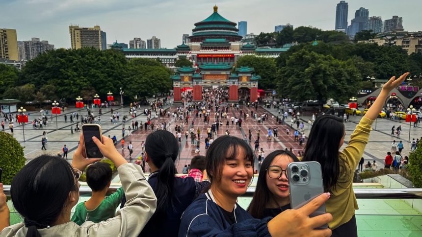 A group of young women take selfies in front of Chongqing's People’s Great Hall during the National Day Golden Week holiday on October 5, 2024, in Chongqing, China.