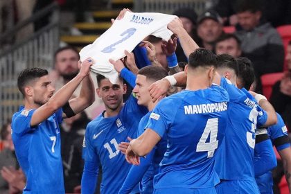 Greece players hold aloft a shirt in memory of George Baldock.