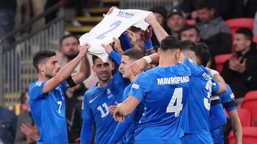 Greece players hold aloft a shirt in memory of George Baldock.