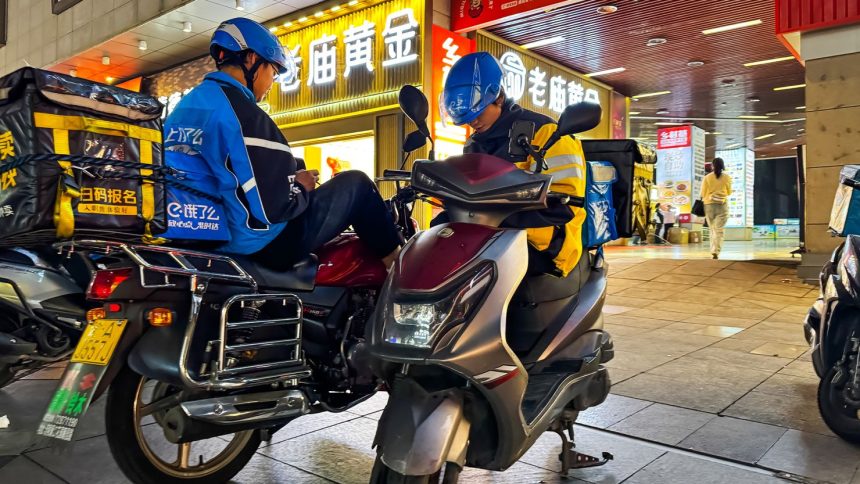 Food delivery riders from different companies wait on their scooters for their next orders on October 7, 2024 in Chongqing, China.