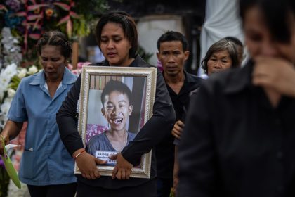 Family members of the victims hold photos of their loved ones during a mass cremation on October 8 for those who died in a bus fire during a school trip last week in Uthai Thani, Thailand.