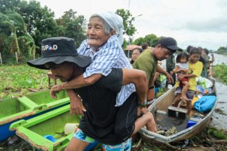 An elderly woman is carried by a volunteer rescuer as residents are evacuated to safer grounds in Bato town, Camarines Sur province south of Manila, Philippines, on October 23, 2024.