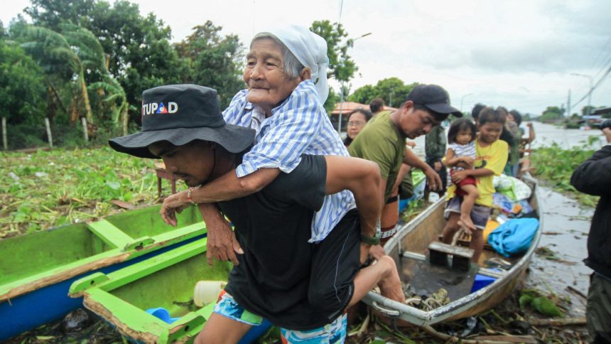 An elderly woman is carried by a volunteer rescuer as residents are evacuated to safer grounds in Bato town, Camarines Sur province south of Manila, Philippines, on October 23, 2024.