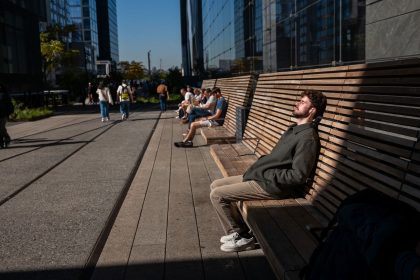 People rest in the sun along the High Line on a sunny and unusually warm day in New York City on October 21, 2024.