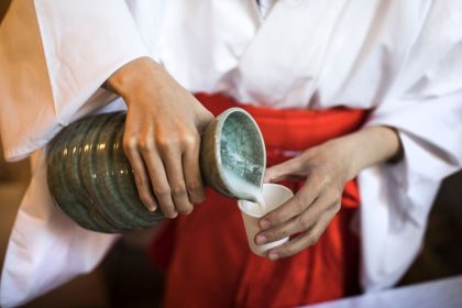 A Japanese attendant pours sake into a cup for visitors at the Koami Shinto shrine.