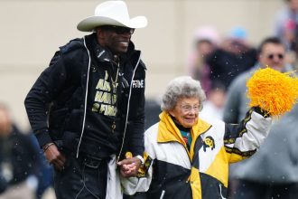 Apr 22, 2023; Boulder, CO, USA; Colorado Buffaloes head coach holds the hand of fan Peggy Coppom before the start of the spring game at Folsom Filed. Mandatory Credit: Ron Chenoy-USA TODAY Sports