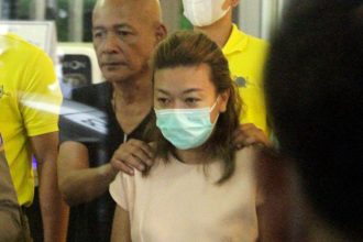 Sararat Rangsiwuthaporn is escorted by officers at a police station in Bangkok, Thailand on April 26, 2023.