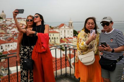 Thousands of locals in Lisbon, Portugal have signed a petition demanding the city cuts down on its tourist lets. Pictured here: people take photos from a popular viewpoint in Lisbon's Alfama neighborhood.