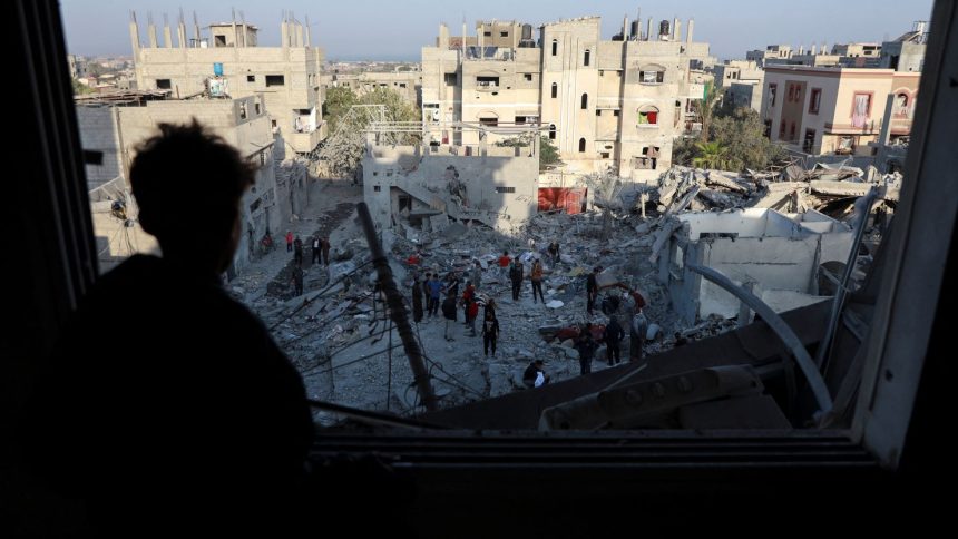 A Palestinian man looks out of a damaged window as he views the site of an Israeli strike on a house, amid the Israel-Hamas conflict, in Nuseirat in the central Gaza Strip on November 7.