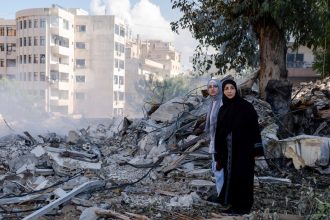 Two women stand next to destruction in the city center of Tyre, following an Israeli airstrike in the southern Lebanese port city.