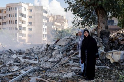 Two women stand next to destruction in the city center of Tyre, following an Israeli airstrike in the southern Lebanese port city.