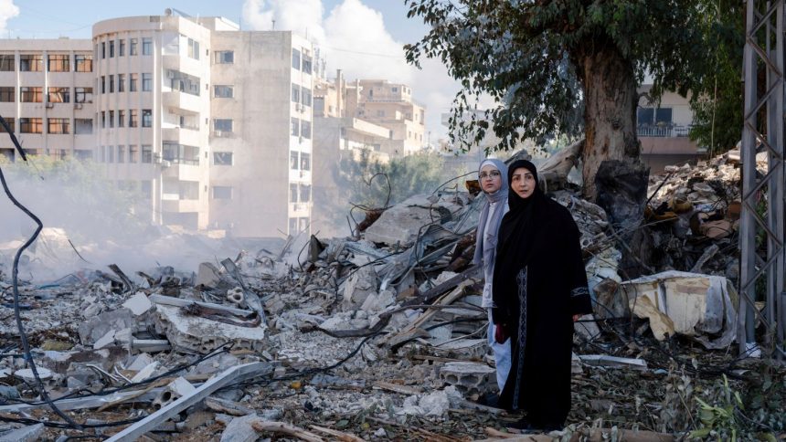 Two women stand next to destruction in the city center of Tyre, following an Israeli airstrike in the southern Lebanese port city.