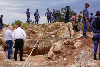 Police officers and private security personnel stand by the opening of a reformed gold mineshaft where illegal miners are trapped in Stilfontein, South Africa.