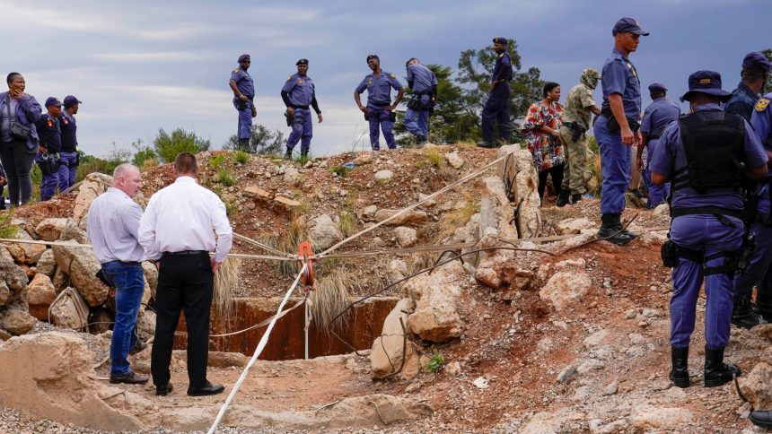 Police officers and private security personnel stand by the opening of a reformed gold mineshaft where illegal miners are trapped in Stilfontein, South Africa.