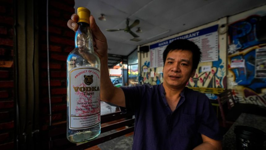 The manager of a hostel in Vang Vieng displays a bottle of Tiger Vodka in Vang Vieng, Laos, on November 19, 2024.