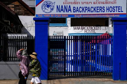 People walk past the closed Nana Backpackers Hostel in Vang Vieng, Laos, on November 23, 2024.