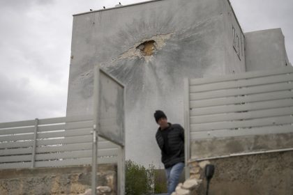 A municipality worker walks next to a residential building hit by a rocket fired from Lebanon, in Shlomi, northern Israel, close to the border with Lebanon on Wednesday.