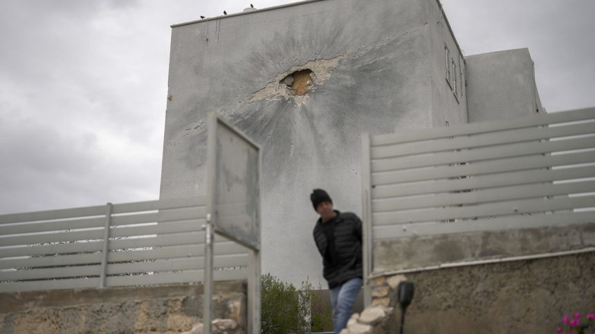 A municipality worker walks next to a residential building hit by a rocket fired from Lebanon, in Shlomi, northern Israel, close to the border with Lebanon on Wednesday.