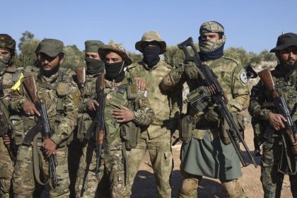 Syrian opposition fighters stand in formation after entering the village of Anjara, western outskirts of Aleppo, Syria, Thursday Nov. 28, 2024, part of their major offensive on government-controlled areas in the country's northwestern Syria. (AP Photo/Omar Albam)