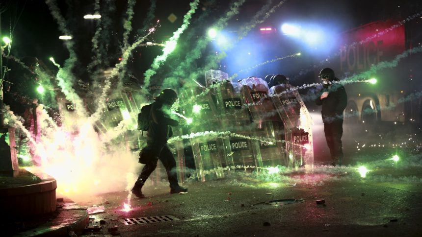 Demonstrators use firecrackers against police as police block a street to prevent protesters rallying against the government's decision to suspend negotiations on joining the European Union for four years, outside the parliament's building in Tbilisi, Georgia, on Nov. 30, 2024.