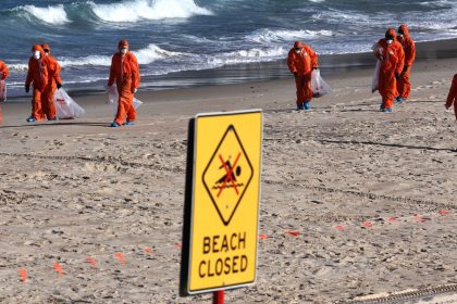 Workers in protective suits conduct a clean-up operation to clear mysterious black balls that washed ashore on Coogee Beach in Sydney, Australia on October 17, 2024.