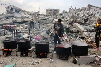 TOPSHOT - A man prepares meals to be distributed to displaced Palestinians in front of a levelled building in Gaza City on November 2, 2024, amid the ongoing war between Israel and Hamas militants. (Photo by Omar AL-QATTAA / AFP) (Photo by OMAR AL-QATTAA/AFP via Getty Images)