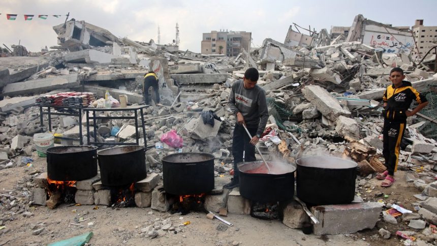 TOPSHOT - A man prepares meals to be distributed to displaced Palestinians in front of a levelled building in Gaza City on November 2, 2024, amid the ongoing war between Israel and Hamas militants. (Photo by Omar AL-QATTAA / AFP) (Photo by OMAR AL-QATTAA/AFP via Getty Images)