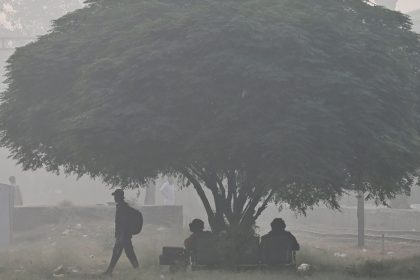 Passengers wait for a train at a railway station amid smoggy conditions in Lahore on November 3, 2024.