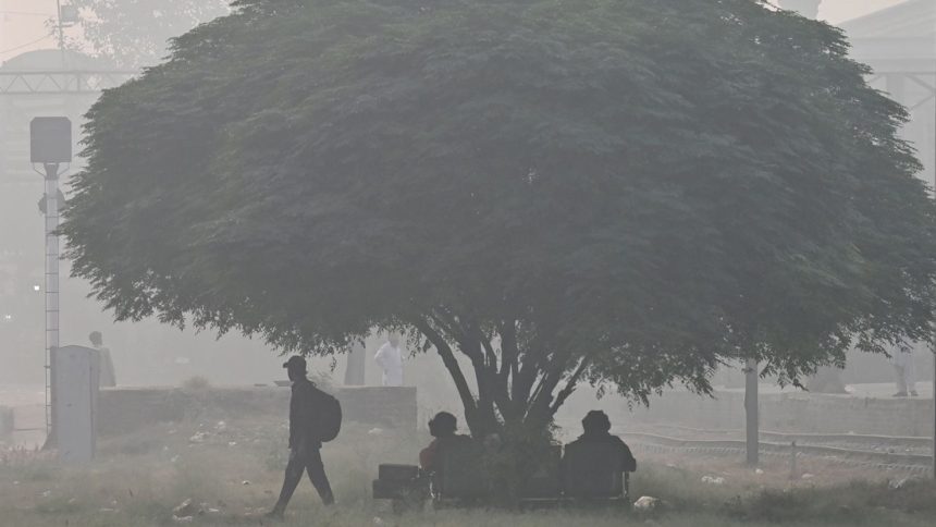 Passengers wait for a train at a railway station amid smoggy conditions in Lahore on November 3, 2024.