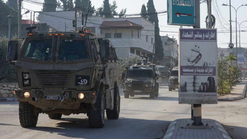 Israeli army vehicles drive down a road during a raid in Qabatiya, south of Jenin city in the occupied West Bank on November 5, 2024.