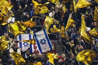 Maccabi supporters wave yellow flags next to Israeli flags during the UEFA Europa League football match between Ajax Amsterdam and Maccabi Tel Aviv at the Johan-Cruijff stadium, in Amsterdam on November 7, 2024.