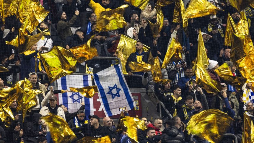 Maccabi supporters wave yellow flags next to Israeli flags during the UEFA Europa League football match between Ajax Amsterdam and Maccabi Tel Aviv at the Johan-Cruijff stadium, in Amsterdam on November 7, 2024.