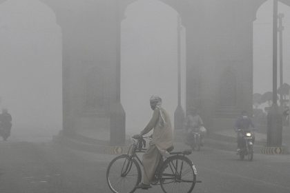 A cyclist rides along a street engulfed in thick smog, in Lahore on November 10, 2024.