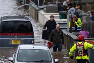 People wade through water on Sion Street in Pontypridd, Wales on November 24, 2024.