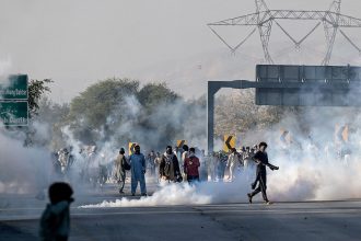 Protesters throw back teargas shells fired by riot policemen during a march to Islamabad demanding the release of former Prime Minister Imran Khan in Hasan Abdal in Punjab province on November 25, 2024.