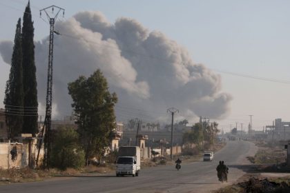 Fighters enter the Rashidin district on the outskirts of Aleppo on their motorbikes with smoke billowing in the background during fighting on November 29, 2024, as Hayat Tahrir al-Sham (HTS) jihadists and allied factions continue their offensive in the Aleppo province against government forces. The jihadists along with Turkey-backed factions launched this week a shock offensive against Syrian regime troops and sparked the deadliest battle the country has seen in years, with the violence killing so far 242 people, according to the Syrian Observatory for Human Rights. The war monitor said most of the victims were combatants on both sides but also including civilians. (Photo by Bakr ALKASEM / AFP) (Photo by BAKR ALKASEM/AFP via Getty Images)