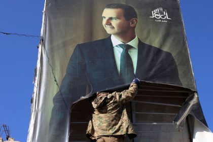 An anti-government fighter tears down a portrait of Syria's President Bashar al-Assad in Aleppo, after jihadists and their allies entered the northern Syrian city, on November 30, 2024.