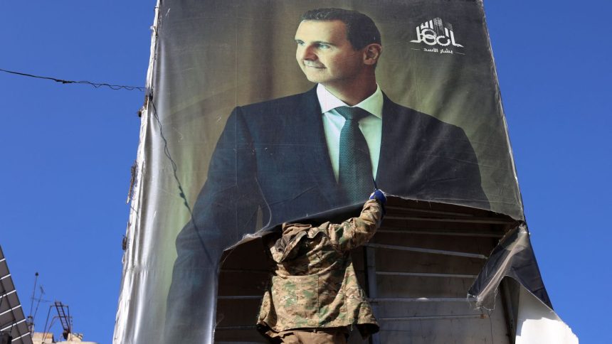 An anti-government fighter tears down a portrait of Syria's President Bashar al-Assad in Aleppo, after jihadists and their allies entered the northern Syrian city, on November 30, 2024.