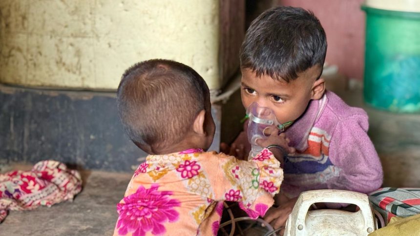 Siblings Chahat, 3 (right) and Diya, 1, play with a nebulizer in their one-room home in a slum in Delhi in November while pollution soars outside.