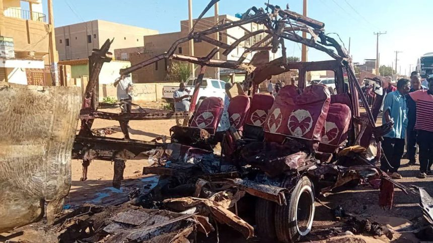 People gather near a destroyed vehicle, following shelling by the Rapid Support Forces, in Omdurman, Sudan, December 10, 2024.