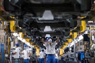 Employees work on a car assembly line at the SAIC General Motors Co. in Wuhan, China, in April 2022.