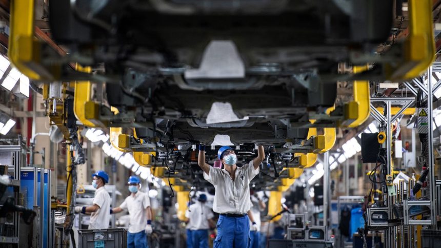 Employees work on a car assembly line at the SAIC General Motors Co. in Wuhan, China, in April 2022.