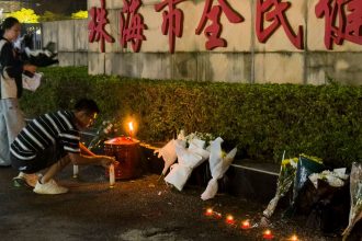 A man lights a candle near flowers placed outside the Zhuhai People's Fitness Plaza, where a man rammed his car into people exercising at the sports center, in Zhuhai, China on November 12, 2024.