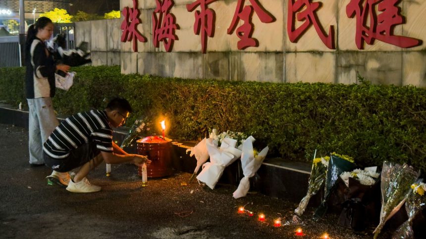 A man lights a candle near flowers placed outside the Zhuhai People's Fitness Plaza, where a man rammed his car into people exercising at the sports center, in Zhuhai, China on November 12, 2024.