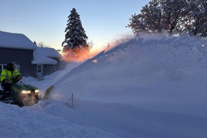 A person clears snow as the sun rises in Lowville, New York, Monday.