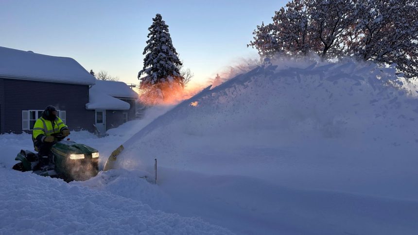 A person clears snow as the sun rises in Lowville, New York, Monday.