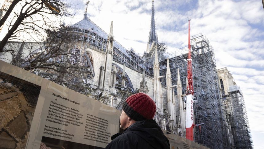 A tourist in front of Notre Dame de Paris Cathedral on the eve of the official reopening five years after the 2019 fire that ravaged the monument.