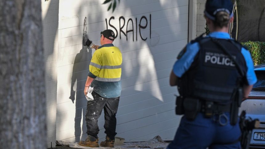 A contractor cleans anti Israel graffiti from a wall in the Sydney suburb of Woollahra, Australia, Wednesday, Dec. 11, 2024.