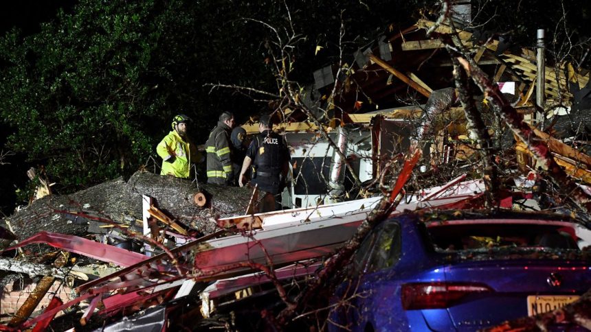 First responders work to free a person after a tree fell on a house in Natchez, Mississippi, on Saturday.